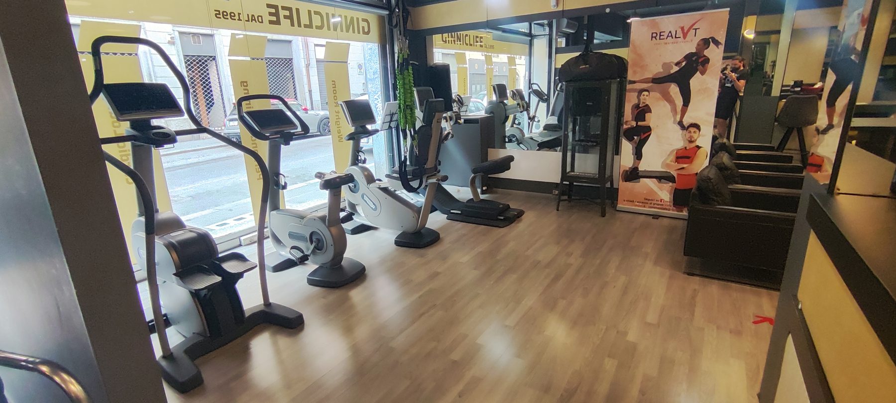 La fila di cyclette e tapis roulant davanti alla vetrina di Ginnic Life, con la scritta sul vetro.